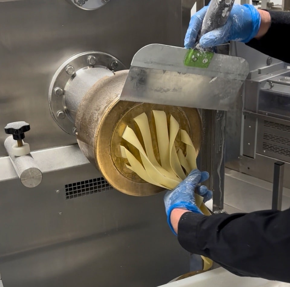 Fresh sourdough pappardelle pasta being cut from a bronze die extruder at VEDE Pasta's Brisbane facility